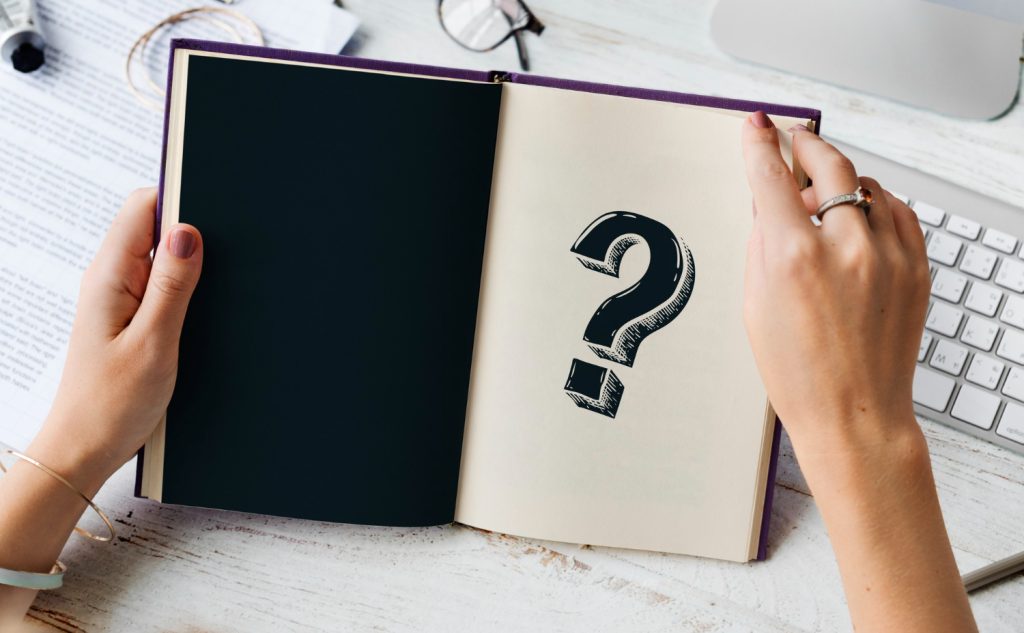 Question mark symbol resting on a book and keyboard as a campaign planning prompt